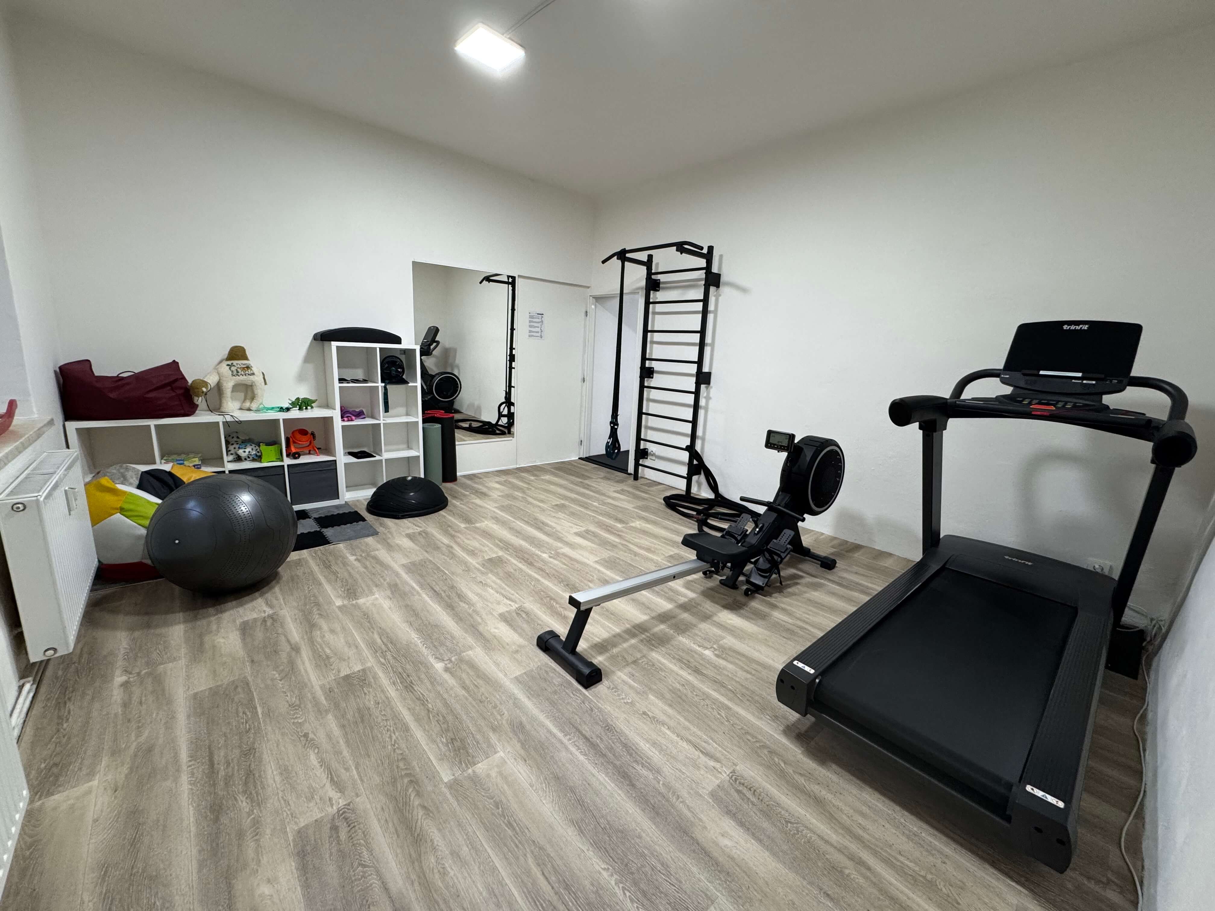 Kompletně vybavená tréninková zóna — veslovací trenažér, běžecký pás, žebřiny a mnoho dalšího. Součástí je i pohodlný dětský koutek, takže můžete trénovat bez starostí.